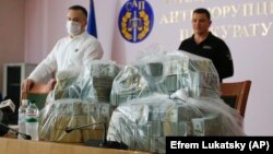 Klymenko's predecessor, Nazar Kholodnytskiy (left) leads a briefing next to $6 million in plastic bags in June 2020, two months before he resigned amid allegations that he helped officials suspected of corruption evade prosecution.