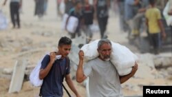 Palestinci nose pomoć koju pruža GHF.