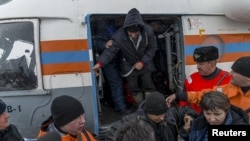 Сотрудники МЧС помогают выжившим морякам затонувшего траулера по их прибытии в Магадан