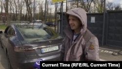 Ukrajinski taksista Anatolij Trepak stoji pored svoje nedavno kupljene Tesle u Kijevu.