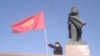 Човек мавта со киргистанско знаме покрај статуата на советскиот лидер Владимир Ленин во центарот на Ош. Градските власти ја симнаа статуата во јуни.
