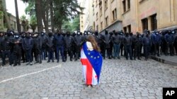 Demonstrantkinja ogrnuta gruzijskom i zastavom EU ispred kordona policije koji blokira pristup zgradi parlamenta tokom protesta u Tbilisiju, 14. maj 2024.