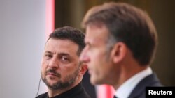 Președintele Zelenski îl ascultă pe Macron la reuniunea de la Paris, de joi.