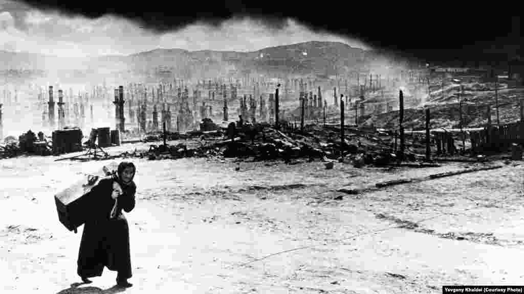 Murmansk, după ce forțele naziste au distrus acest oraș din nordvestul Rusiei cu bombe incendiare în 1942. Khaldei își amintește că femeia l-a admonestat spunîndu-i &bdquo;De ce nu te duci la Berlin să fotografiezi cum îl bombardează piloțiii noștri!?&rdquo;. Tînărul fotograf i-a promis că dacă va ajunge vreodată în Germania va face exact asta.