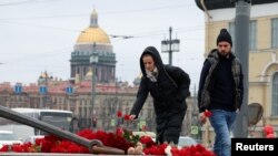 Virágot helyeznek el az áldozatok emlékére egy ideiglenes emlékműnél Szentpéterváron 2024. március 24-én