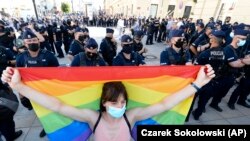 Egy nő szivárványos zászlót tart a szélsőjobboldali aktivisták tüntetése ellen Varsóban, 2020. augusztus 16-án.