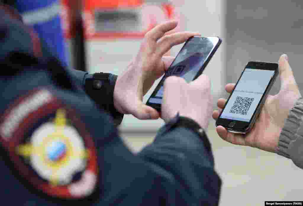 Полициски службеник гледа на QR-кодот на паметен телефон на патник за време на проверка на лична карта на станицата &bdquo;Планернаја&ldquo; во московското метро на 15 април во Москва, Русија. Според системот за дигитални дозволи, воведен од московската влада, кој стана задолжителен од 15 април, луѓето треба да аплицираат за дозволи за патување со&nbsp; јавен превоз или возило низ градот.