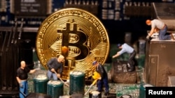 Prikaz virtualne valute Bitcoin i figure male igračke postavljene na matičnu ploču računala na ilustraciji, januar, 2021. 