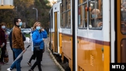 A koronavírus-járvány miatt maszkot viselő utasok egy budapesti villamosmegállóban 2020. október 31-én