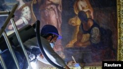 Работник бърше прах от картина във Версайския дворец край Париж. Франция се подготвя да приема туристи от Европа 