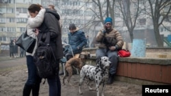 Locuitorii unui bloc de apartamente de 18 etaje din Kiev, grav avariat de atacurile rusești, stau într-un parc, 7 februarie 2024.