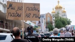 Мъж държи плакат с надпис: "Ние не сме роби, роби ние не сме" - популярен цитат от първия съветски буквар за първи клас (1919 г.) Снимката е архивна.