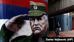 Žena sa zaštitnom maskom prolazi pored grafita s likom ratnog generala Vojske Republike Srpske Ratka Mladića, u Beogradu 12. novembra 2020.