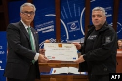 ევროპის საბჭოს საპარლამენტო ასამბლეის პრეზიდენტი თეოდოროს რუსოპულოსი (მარცხენა) და უკრაინელი ჟურნალისტი და ადამიანის უფლებათა დამცველი მაქსიმ ბუტკევიჩი