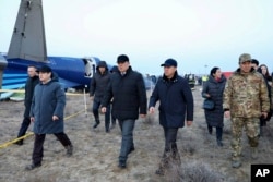 Члены госкомиссии по расследованию и местные чиновники проходят мимо обломков Embraer 190 авиакомпании Azerbaijan Airlines. 26 октября 2024 года