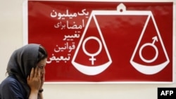 Иранка поминува пред плакат на кој пишува „Еден милион потписи за промена на пристрасните закони“.