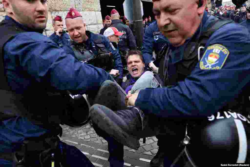 Полицейские несут протестующего, в то время как демонстранты блокируют вход в гараж парламента в день голосования венгерского парламента по поправкам к конституции, нацеленным против ЛГБТК-сообщества, Будапешт, Венгрия, 14 апреля 2025 года. REUTERS/Bernadett Szabo