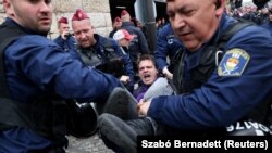 Rendőrök visznek el egy tüntetőt a Parlament garázsának bejáratát elől 2025. április 14-én