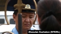 Полицейский у ворот здания комитета уголовно-исполнительной системы беседует с родственниками осужденных, которые пытались встретиться с представителями ведомства. Астана, 14 августа 2010 года.