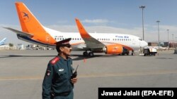 Авганистански полицаец стои на стража пред Боинг 737-500 на авганистанскиот носач Кам Ер на меѓународниот аеродром во Кабул, архивска фотографија