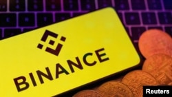 Пернетақта үстінде жатқан смартфонның экранындағы Binance логотипі және криптовалюталар кескіндері көрсетілген. 2023 жылдың 8 маусымында түсірілген сурет, REUTERS/Dado Ruvic/Illustration/File Photo.
