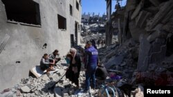 Palestinka sa djetetom hoda na mjestu izraelskog napada na kuću, u gradu Gaza, 24. marta 2025.