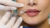 Close-up lips augmentation injections for attractive girl. Plastic surgeon does injection in lip in medical clinic.