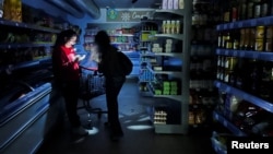 Сотрудница супермаркета сопровождает покупательницу в время масштабного отключения электричества. Барселона, 28 апреля 