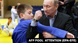 Архивное фото. Тогдашний премьер-министр России Владимир Путин показывает юноше прием по дзюдо в спортивном комплексе в сибирском городе Кемерово, 24 января 2012 года 