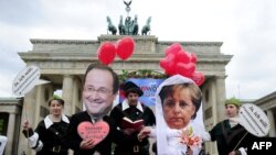 NGO aktivisti sa maskama Angele Merkel i Francoisa Hollanda, Berlin, maj 2012.