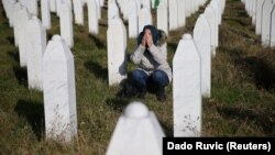 Жена се моли на гробот на убиените членови на нејзиното семејство во Меморијалниот центар Поточари во близина на Сребреница