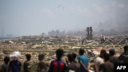 Palestinci posmatraju palete s humanitarnom pomoći kako se spuštaju padobranima iznad Nuseirata, u centralnom Pojasu Gaze, 5. avgusta 2025.