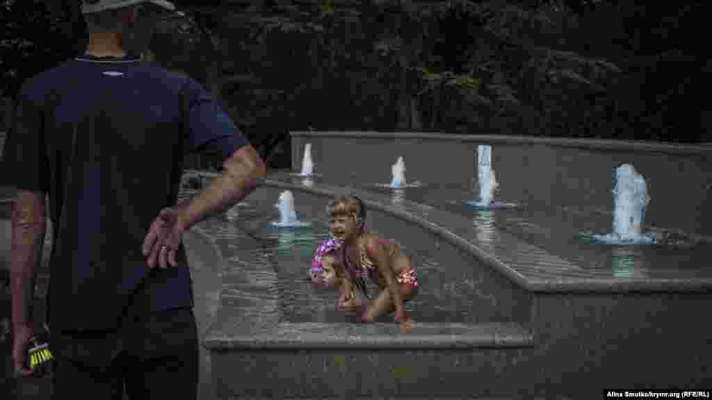 Мужчина собирается чистить фонтан, в котором купаются дети