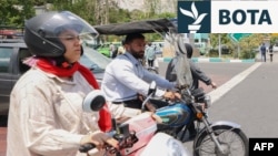 Një grua dhe një burrë me motoçikletat e tyre në qendër të Teheranit. Fotografi e majit 2024.