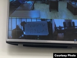 Часть фигурантов "Баймакского дела" в суде по видеоконференцсвязи, 6 мая 2025 года. В руках: плакат на башкирском языке "Кыркты живи!" против намеченных разработок медных месторождений на хребте Крыктытау в Башкортостане