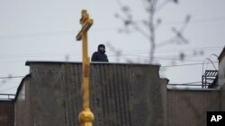 Полицейски служител пази на покрива на жилищна сграда близо до църквата