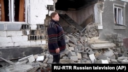 Žena stoji pored svoje kuće koja je oštećena u borbama ukrajinske vojske i proruskih separatista, 18. februar 2020.