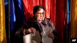 Жена излиза от кабина за гласуване в Букурещ, 24 ноември 2024 г. Към 15:00 ч. избирателната активност е била 32% спрямо 29,2% по същото време на вота през 2019 г.