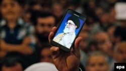 Një Iranian mban në duar një telefon, ku shfaqet fotografia e liderit suprem të Iranit, Ayatollah Ali Khamenei 