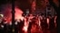 A flare burns as Serbian Riot Police move towards protesters as tens of thousands gather in central Belgrade to issue an "ultimatum" to the populist government to call early elections after months of student-led strikes across the country, in Belgrade, on