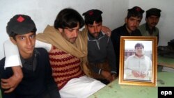 هنګو: د اعتزاز احسن ورور مجتبی حسن چې په ناستو کې له کیڼه اړخ دوهم دی، د خپل سرښندونکي ورور له تصویر سره ویر کوي چې په سرکاري سکول کې یې یوځانمرګی بریدګر ته غاړه ورکړه او سلګونه ماشومان یې وژغورل. ۲۰۱۴، د جنورۍ ۱۰مه نېټه
