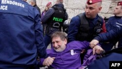Poliția îndepărtând cu forța protestatarii care încercau să blocheze o intrare în parlamentul de la Budapesta, înainte de votul asupra amendamentelor constituționale anti LGBT+, pe 14 aprilie 2025