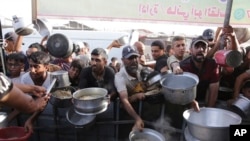 Bărbați palestinieni primesc ajutor alimentar în Khan Younis. 15 iunie 2024.