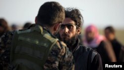 Borac Sirijskih demokratskih snaga provjerava zarobljenog militanta ekstremističke organizacije Islamska države Iraka i Levanta.