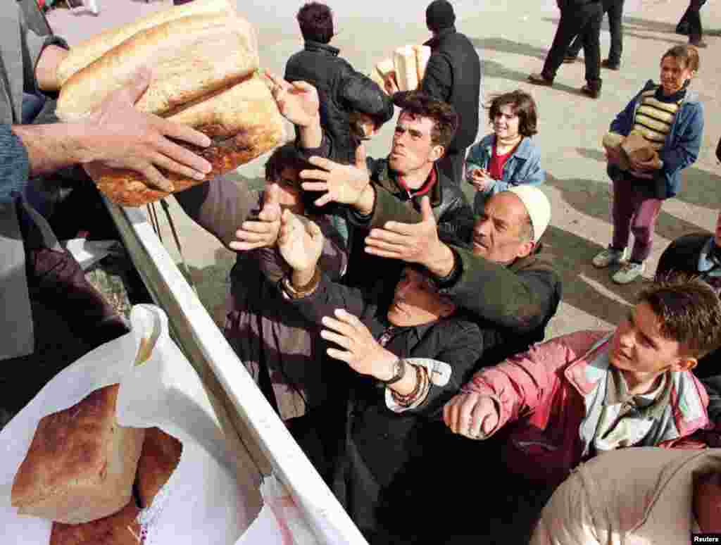 Refugjatë shqiptarë nga Kosova, duke marrë bukë në Kukës pasi kanë ikur nga luftimet që po zhvilloheshin në vendbanimet e tyre, 30 mars 1999. Arben Celi/Reuters.&nbsp; 