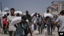 Palestinezët duke bartur në krah thasë me miell. 27 korrik 2025. 