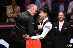 Марк Уилямс (вляво) поздравява Джао Синтонг за победата му на финала за световната титла по снукър пред погледа на българската съдия Десислава Божилова, която ръководи срещата, 5 май 2025 г.