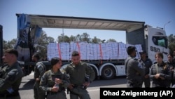 Грузовик с гуманитарной помощью для сектора Газа направляется к контрольно-пропускному пункту Керем-Шалом, в то время как сотрудники пограничной полиции Израиля не позволяют протестующим перекрыть ему дорогу. Юг Израиля, 21 мая 2025 года