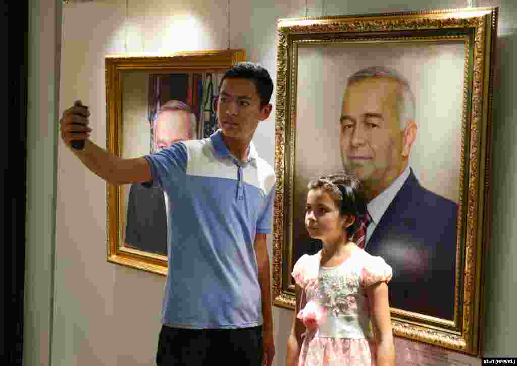 Млади посетители на музея си правят селфи пред платно с Каримов.