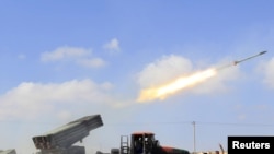 Rebel fighters fire a rocket west of the rebel-held city of Misurata on June 17.
